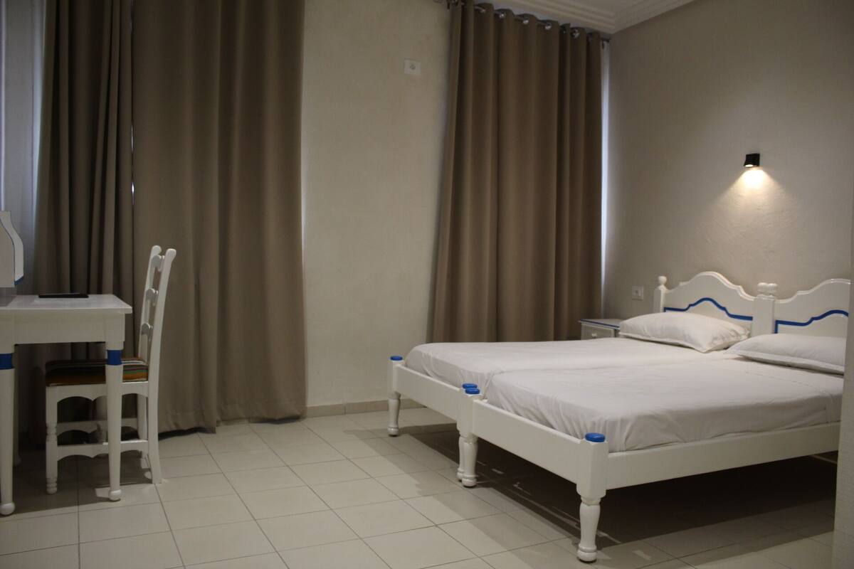 A bedroom with a bed, a desk, and a chair.