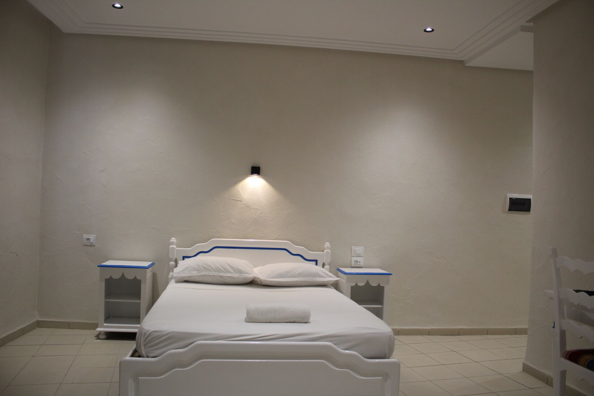Een slaapkamer met een bed, nachtkastjes en een wandlamp.
