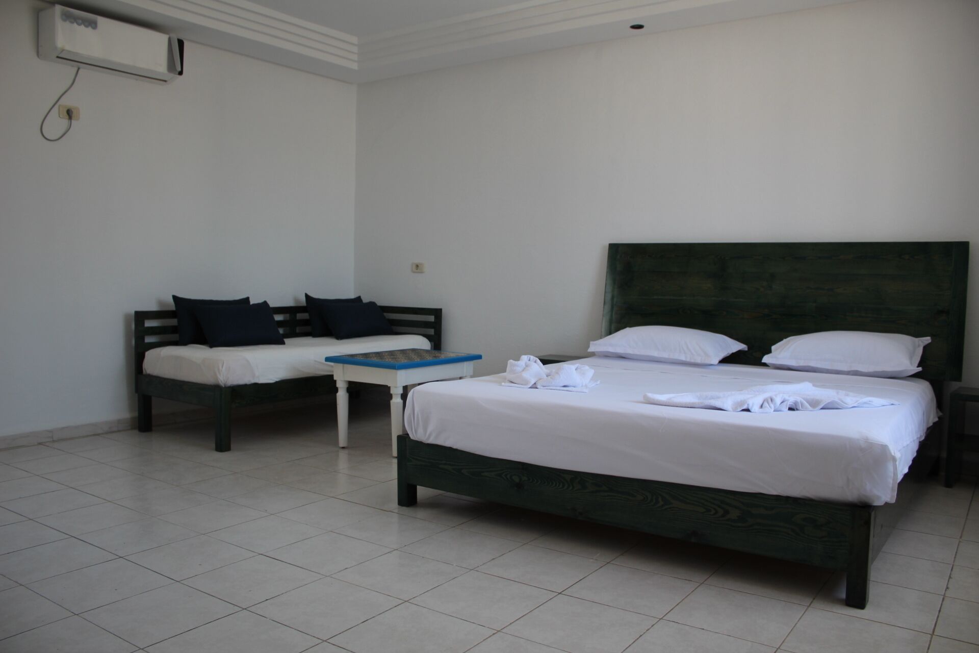 Una habitación de hotel con una cama grande, otra más pequeña, un escritorio y una silla.