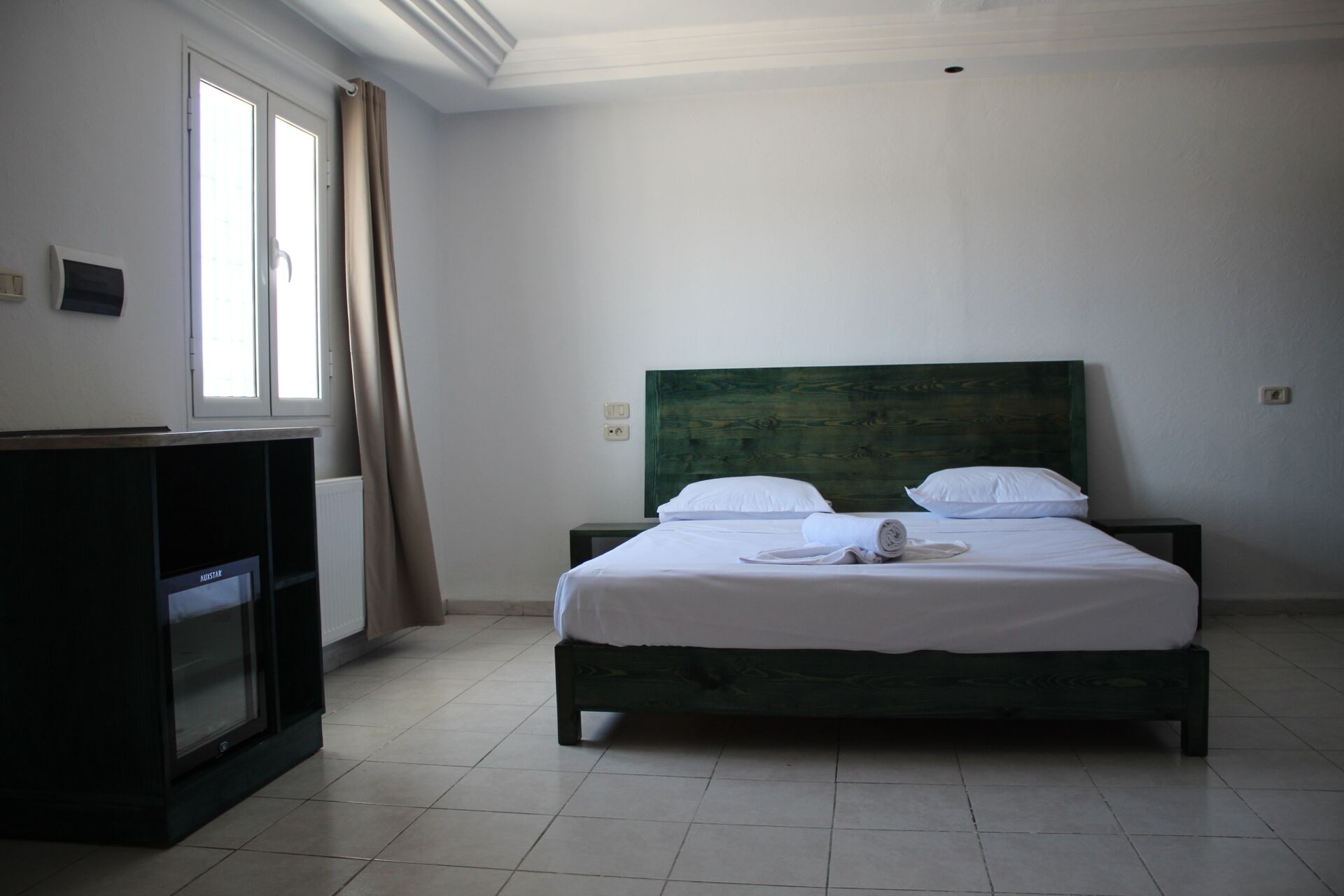 Une chambre d’hôtel avec un lit, un bureau et une fenêtre avec des rideaux.