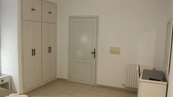 A room with a wardrobe, a door, a radiator, and a small table.