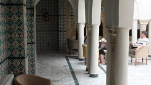 A corridor with patterned walls, arches, and seating areas. - Hôtel Medina (Sousse)