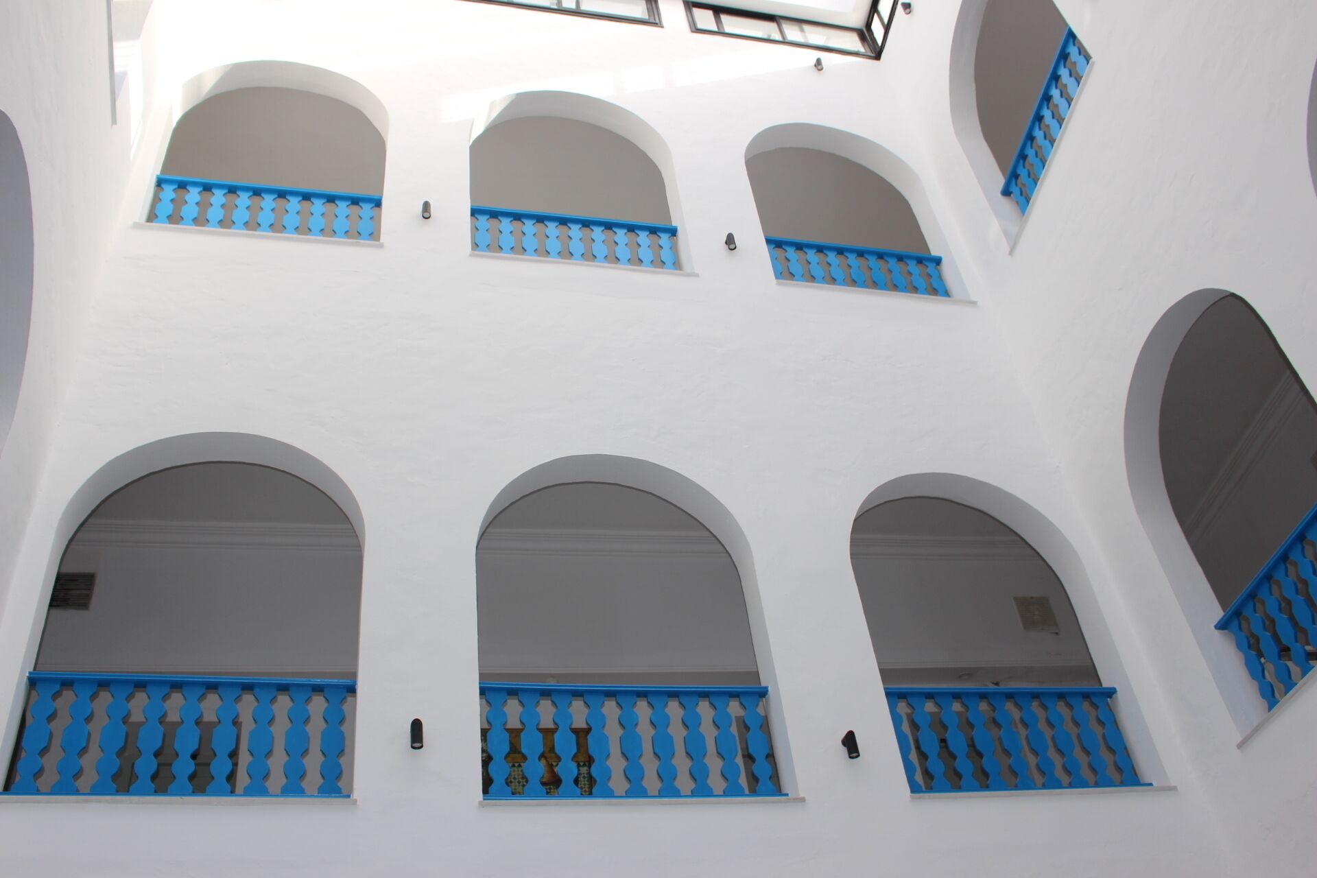 Un edificio blanco con varias ventanas arqueadas y marcos azules.