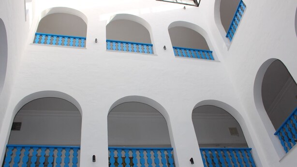 A white building with multiple arched windows and blue window frames. - Hôtel Medina (Sousse)