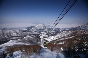 A cable car ascending a snowy mountain with a clear view of the landscape below. - Ryuoo Park Hotel (Yamanouchi)