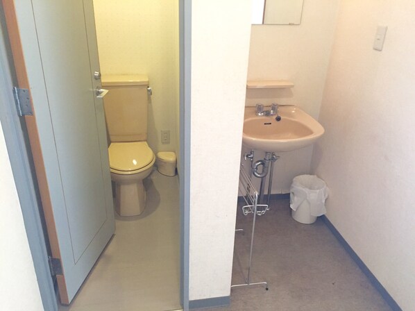 A bathroom with a toilet, sink, and a trash bin.