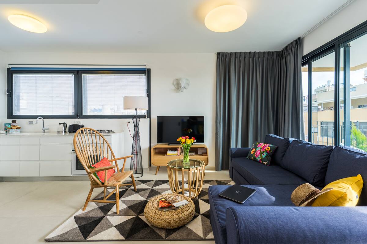 A modern living room with a sofa, a chair, a coffee table, and a TV.