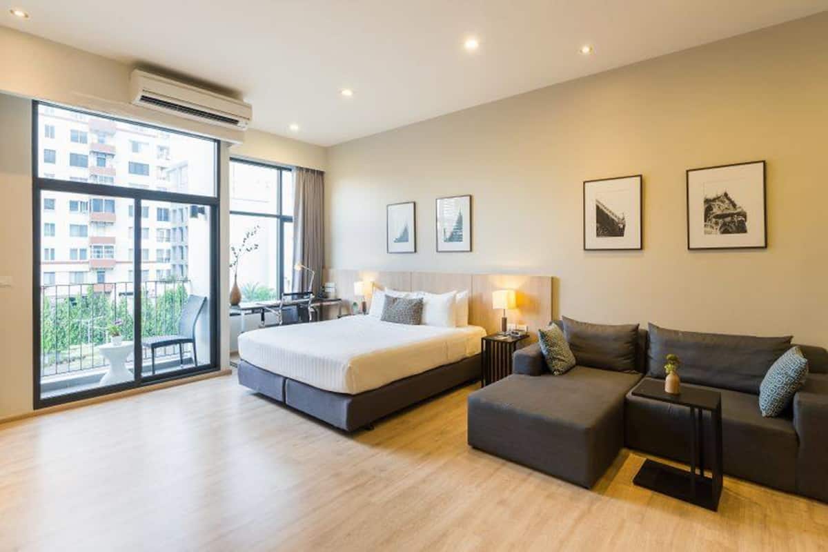 Una habitación de hotel moderna con una cama grande, un sofá y un balcón con vistas a la ciudad.