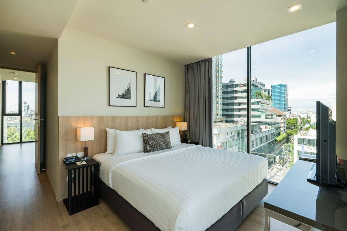 Una habitación de hotel moderna con una cama grande, un escritorio y vistas a la ciudad.