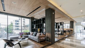 Ein modernes Wohnzimmer mit einer Couch, einem Couchtisch und Sesseln, großen Fenstern mit Blick auf die Stadt und einem Essbereich mit hohem Tisch und Stühlen.