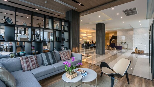 Eine moderne Hotelhalle mit einer grauen Couch, einem Couchtisch und einer Sitzecke mit einem Sessel.