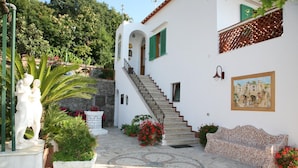 A white building with a staircase, a statue, and potted plants. - B&B Il Grappolo (Anacapri)