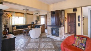 A spacious living room with a fireplace, a sofa set, and a red armchair.