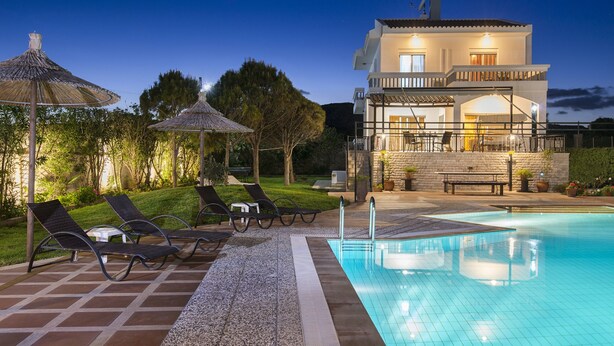 A modern two-story house with a swimming pool, outdoor seating, and a well-maintained garden.