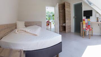 A bedroom with a bed, a desk with a TV, and a wooden wardrobe.