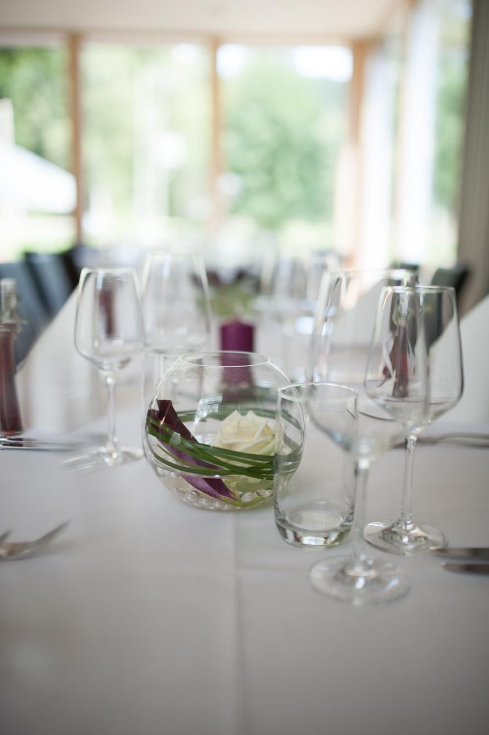 A table set with wine glasses and a bowl containing a flower arrangement.