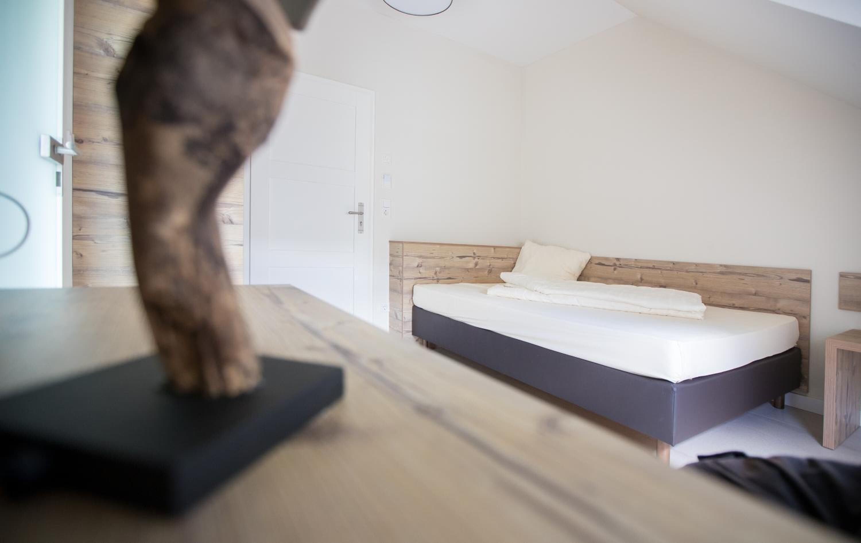 A bedroom with a wooden headboard, a bed with white linens, and a wooden nightstand.