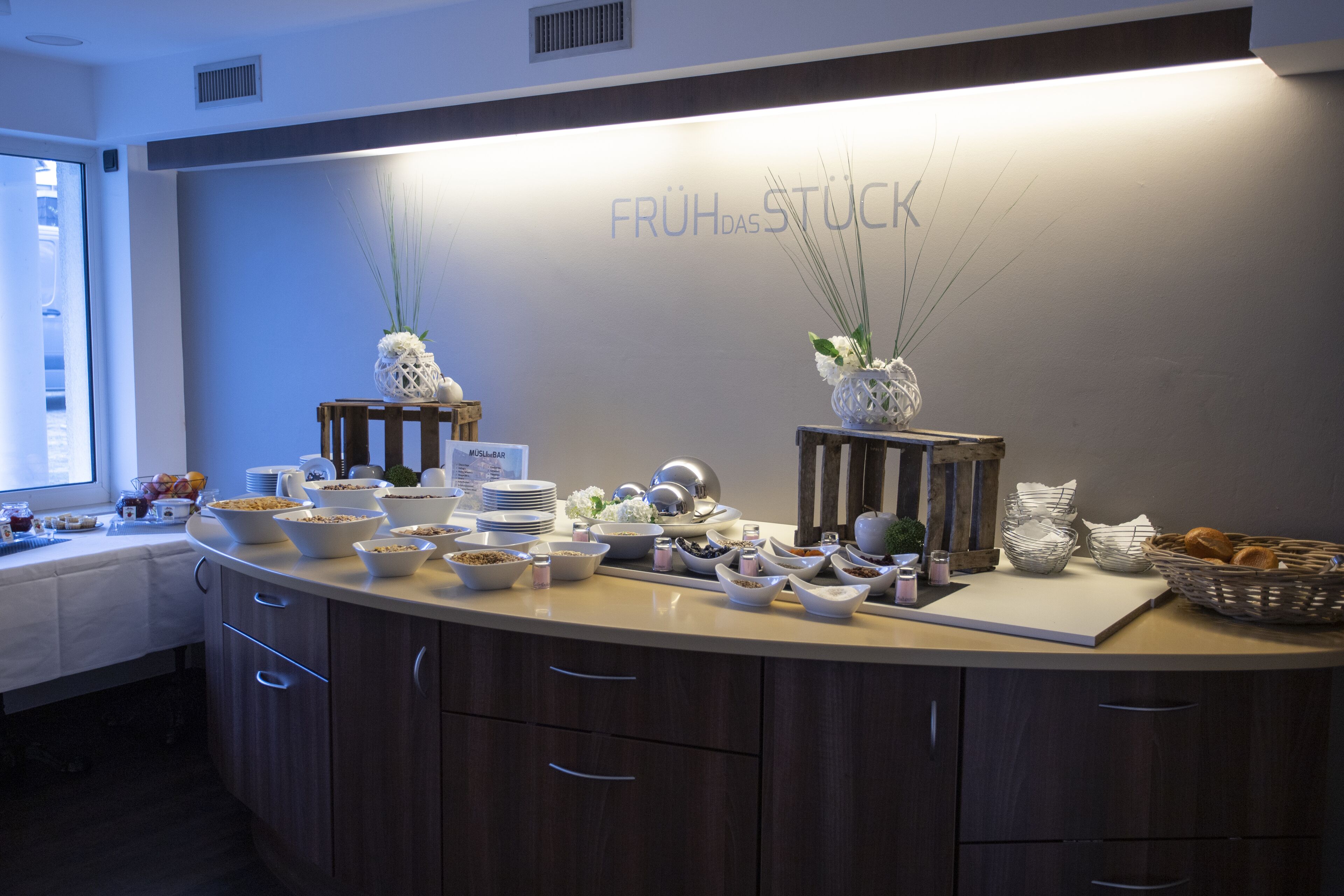 A breakfast buffet with various food items and decorative vases on a wooden counter.
