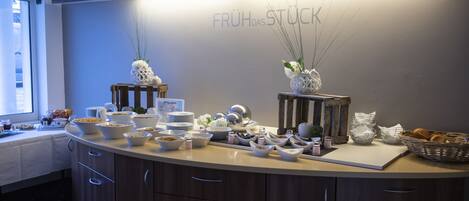 A breakfast buffet with various food items and decorative vases on a wooden counter.