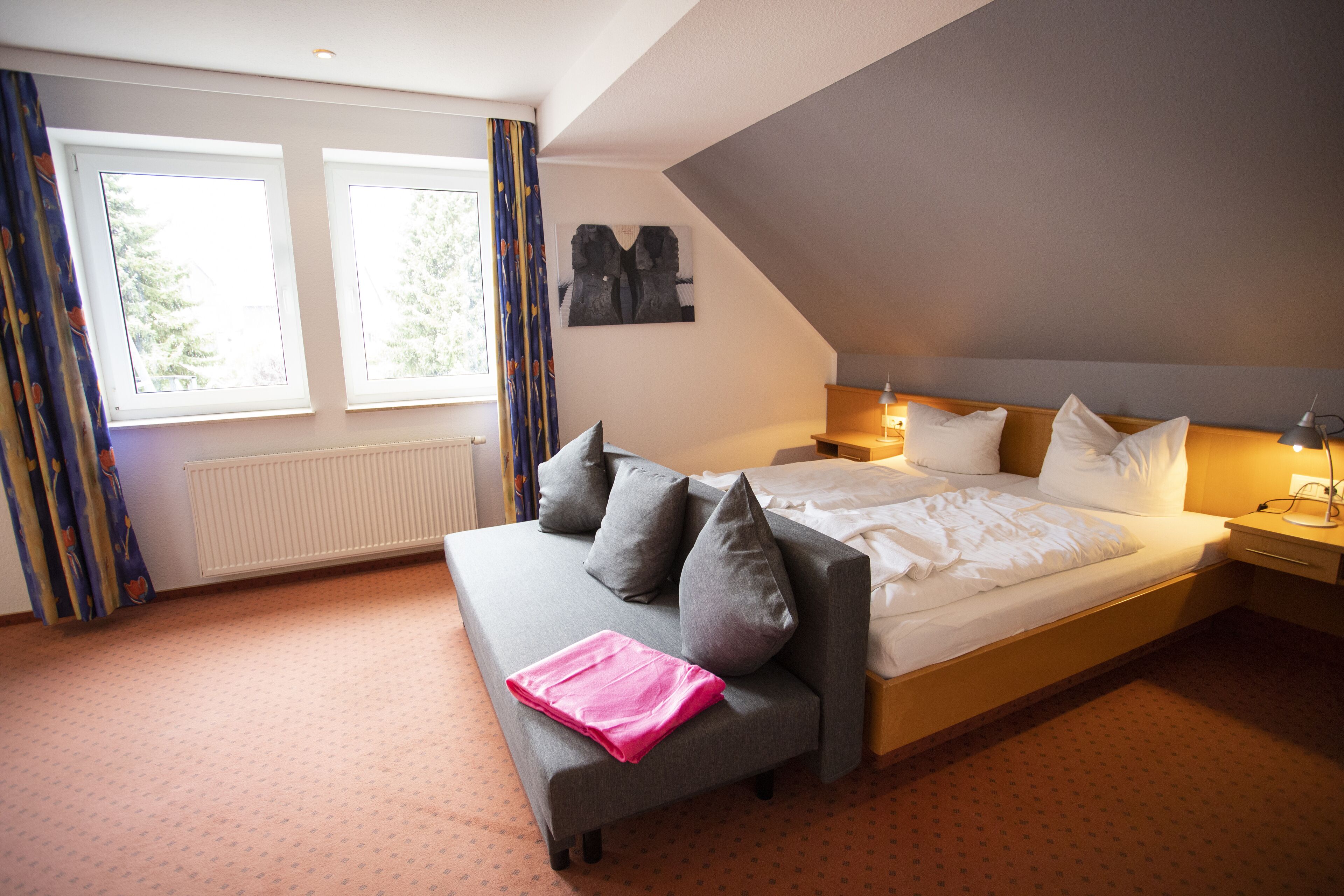A bedroom with a large bed, a sofa, and a window with curtains.