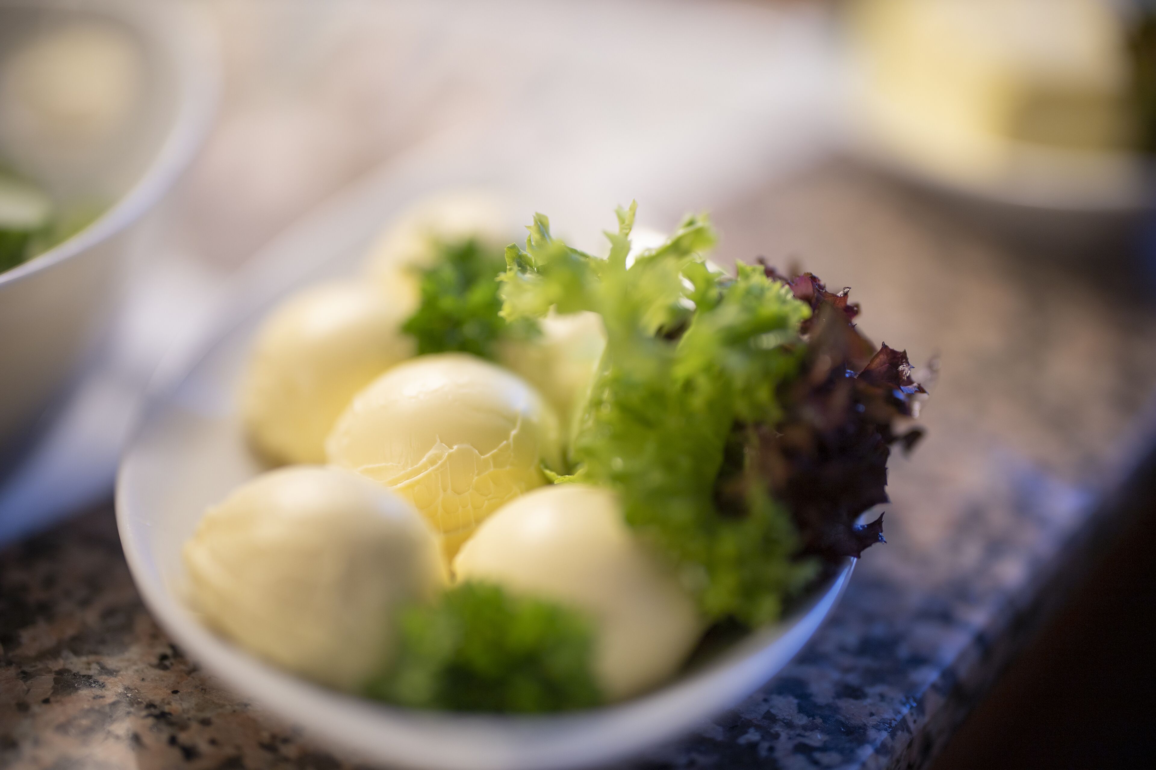A plate with boiled eggs and lettuce on a granite countertop.