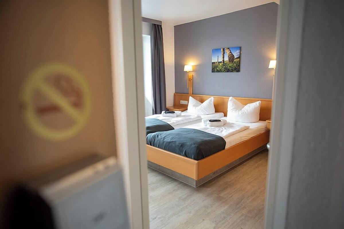 A hotel room with a bed, bedside tables, a lamp, and a painting on the wall.