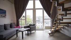 Een moderne woonkamer met een grijze bank, een salontafel en een trap met houten treden.