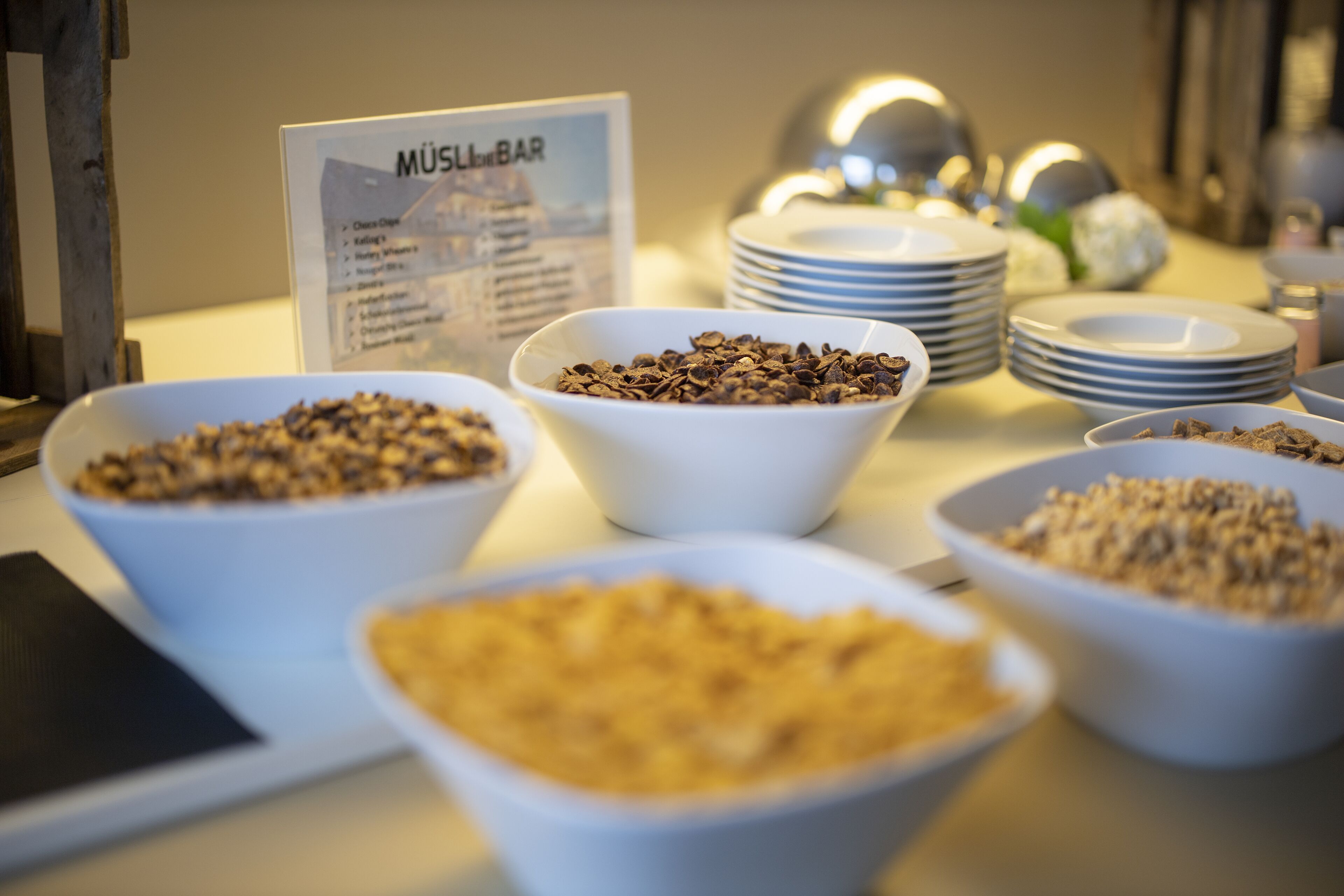 Una mesa de buffet con diferentes alimentos y un letrero que indica la sección 'MÜSLIBAR'.