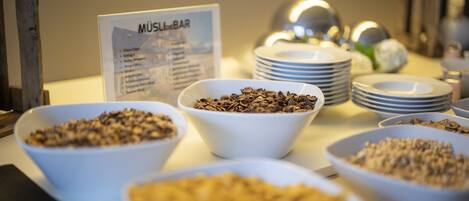 Una mesa de buffet con diferentes alimentos y un letrero que indica la sección 'MÜSLIBAR'.