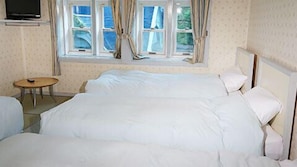 A hotel room with two beds, a small round table, and a TV on the wall.