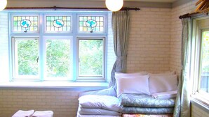 Una habitación con cama, ventana con cortinas y una mesa con toallas.