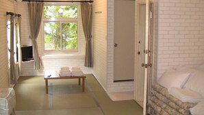 Una habitación con una cama, una mesa con toallas, un televisor en un estante y una puerta.