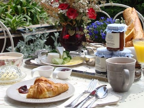 A breakfast table with croissants, cheese, fruits, and a vase of flowers. - Bed & Breakfast No. 31 im Rosengarten (Kapellen-Drusweiler)