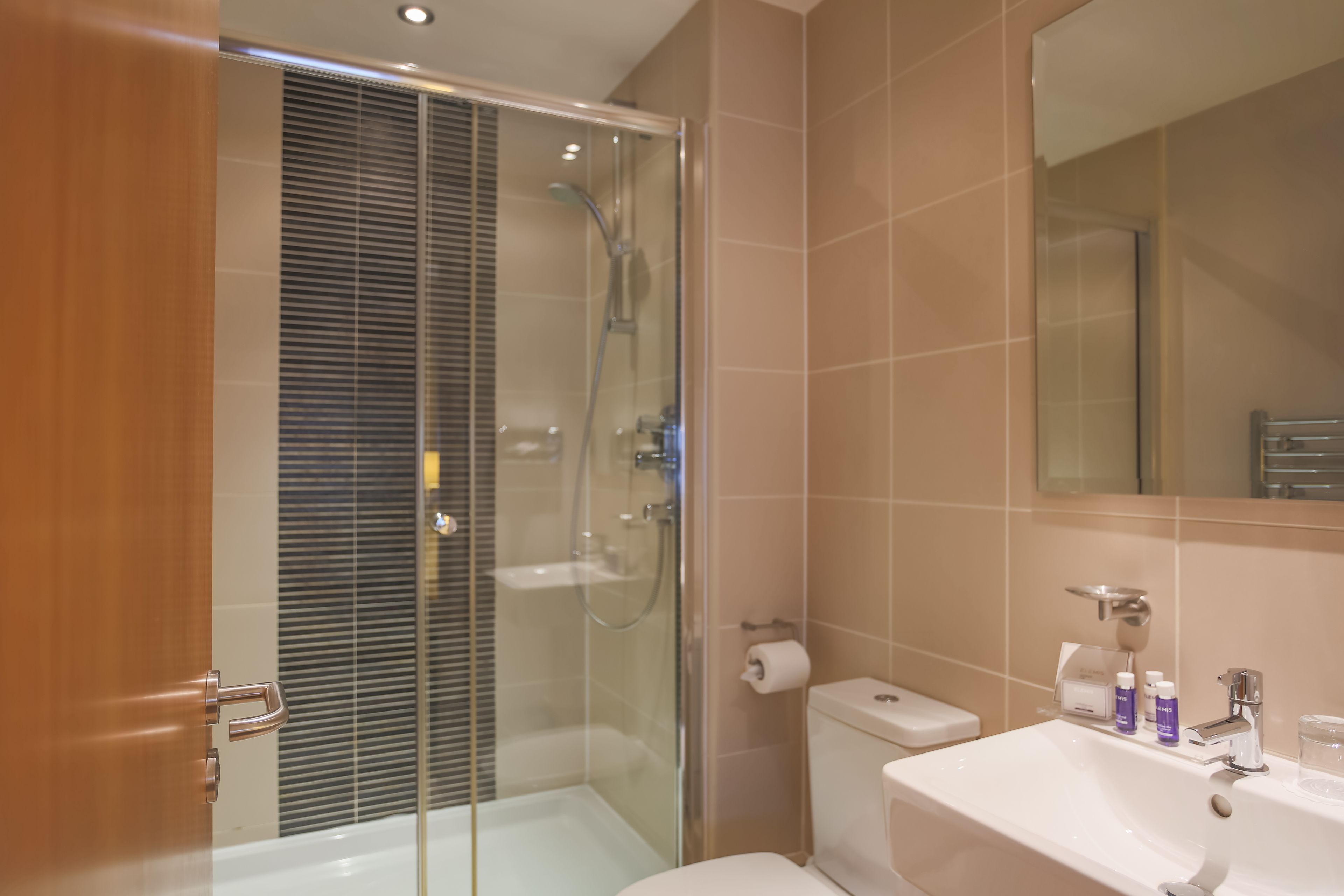 Ein modernes Badezimmer mit einer Duschkabine, einem weißen Waschbecken und einer Toilette.