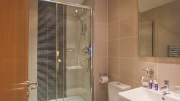 Ein modernes Badezimmer mit einer Duschkabine, einem weißen Waschbecken und einer Toilette.