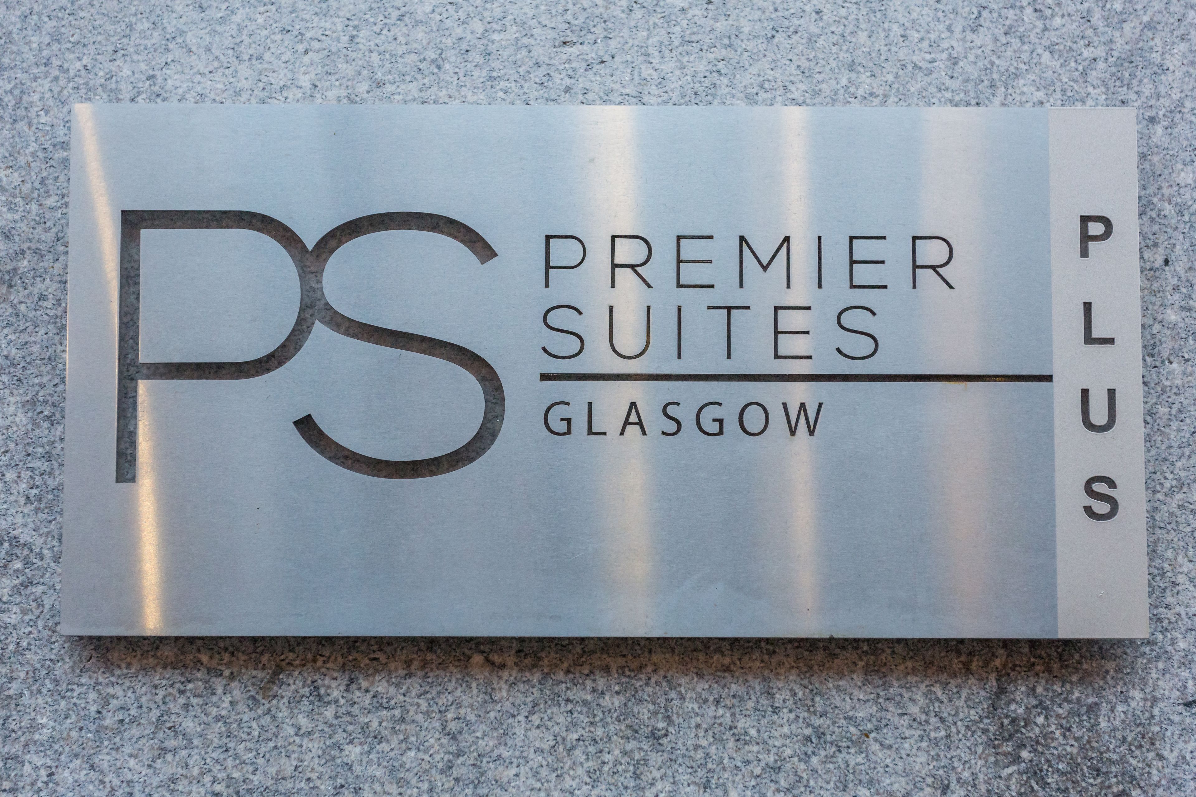 Naamplaatje voor Premier Suites Glasgow, met een opvallend logo en de naam van het hotel.