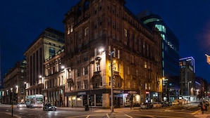 Un edificio histórico con entrada en esquina, ventanas amplias y un moderno añadido de cristal.