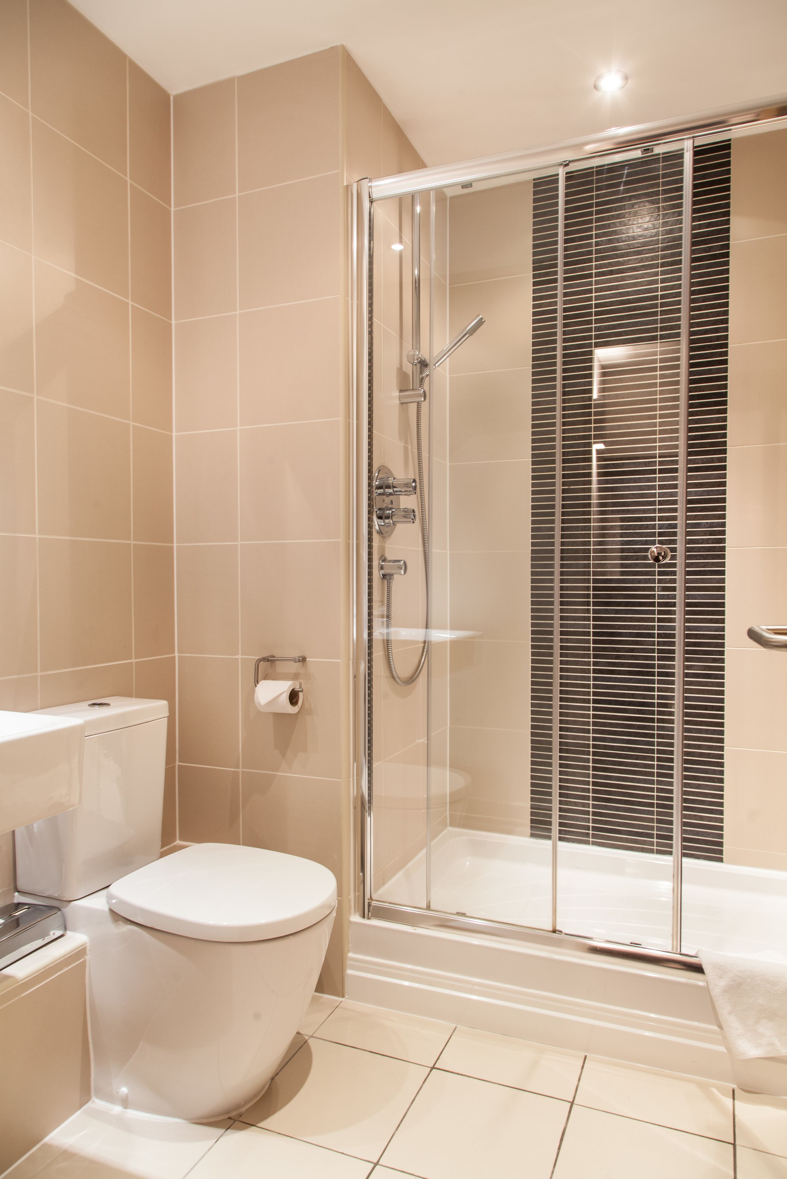 A modern bathroom with a glass-enclosed shower, a white toilet, and a bathtub.