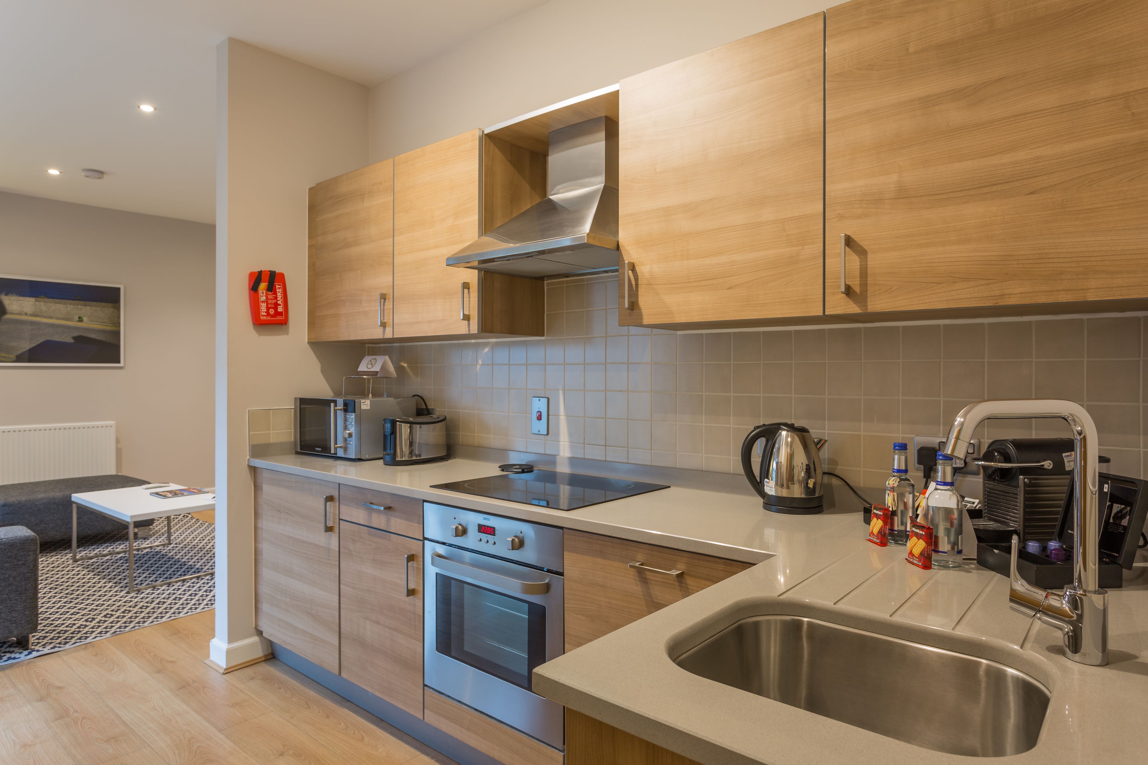 A modern kitchen with wooden cabinets, a stainless steel sink, and a built-in oven.