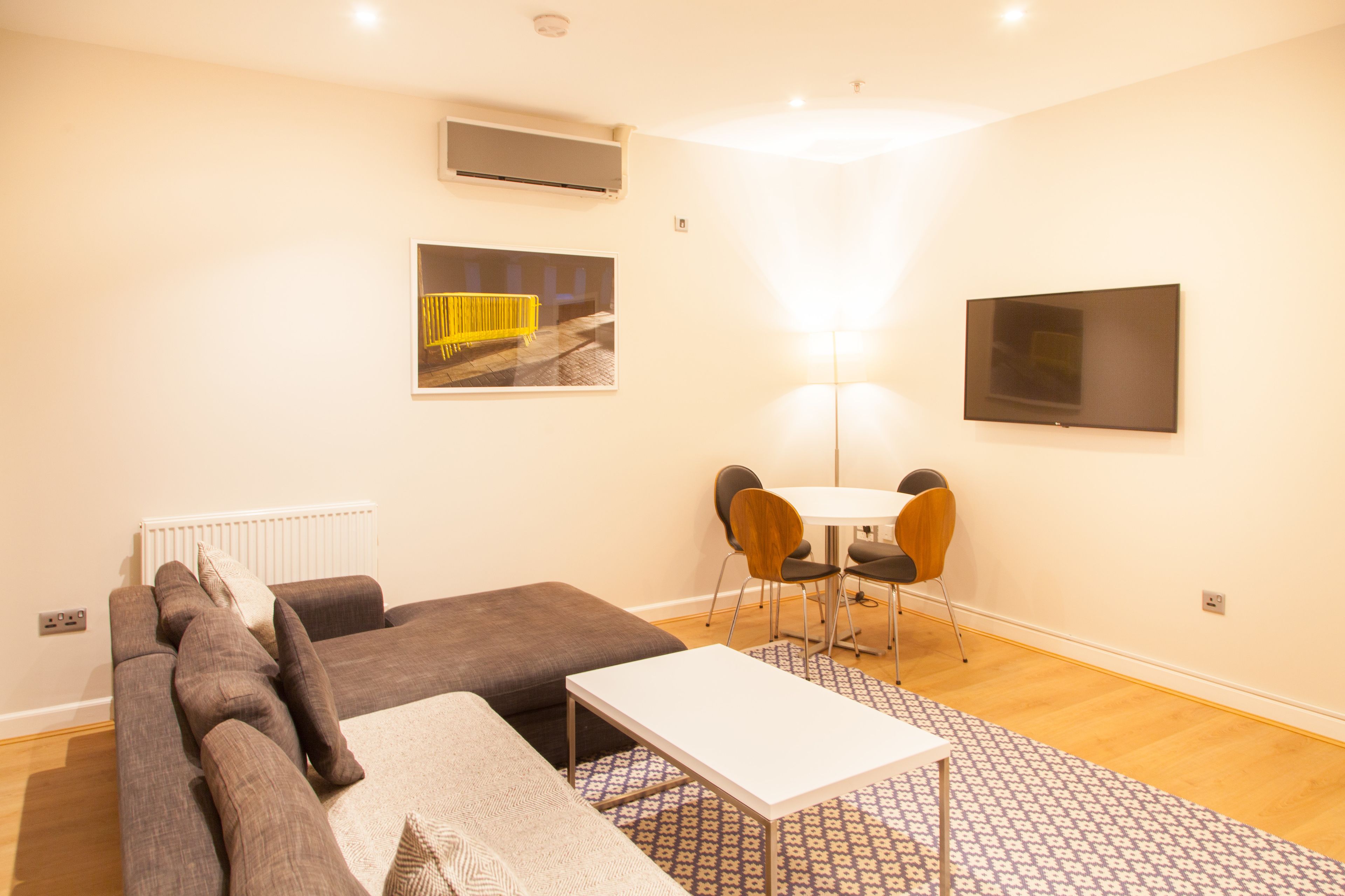 A modern living room with a sofa, a small table, and a dining area with chairs.