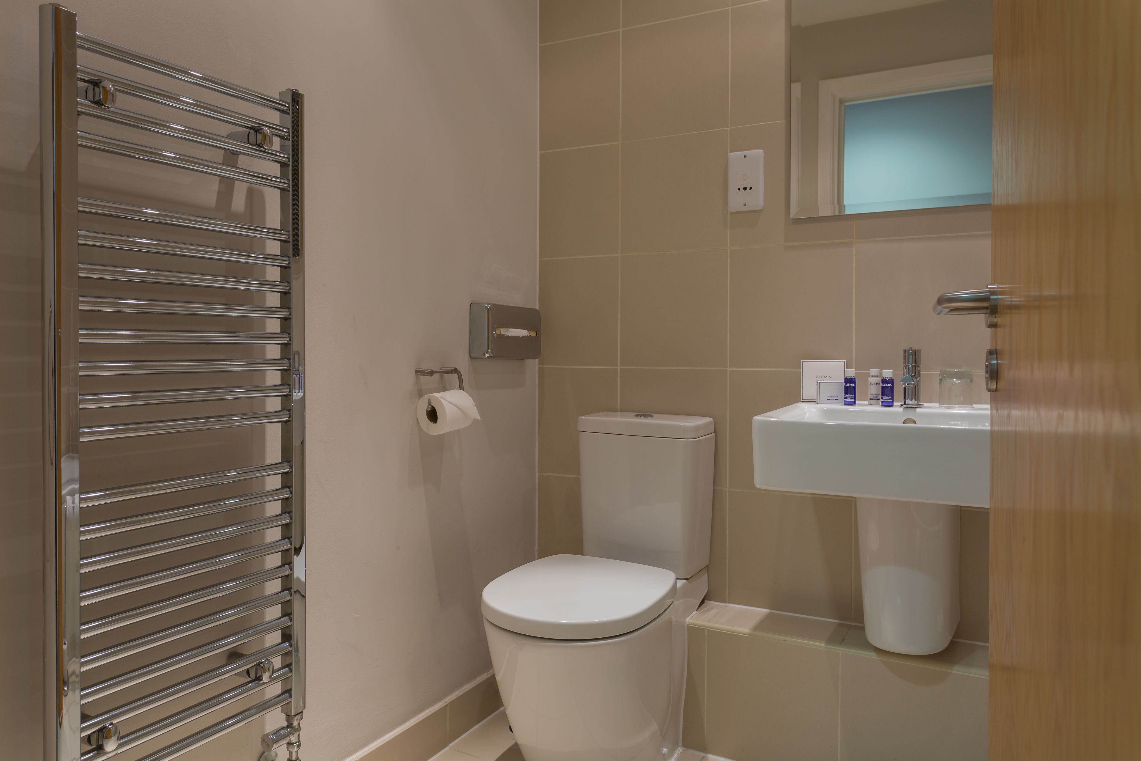 Een moderne badkamer met toilet, wastafel en handdoekhouder.