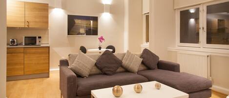 A modern living room with a sofa, a coffee table, and a dining area with a table and chairs.