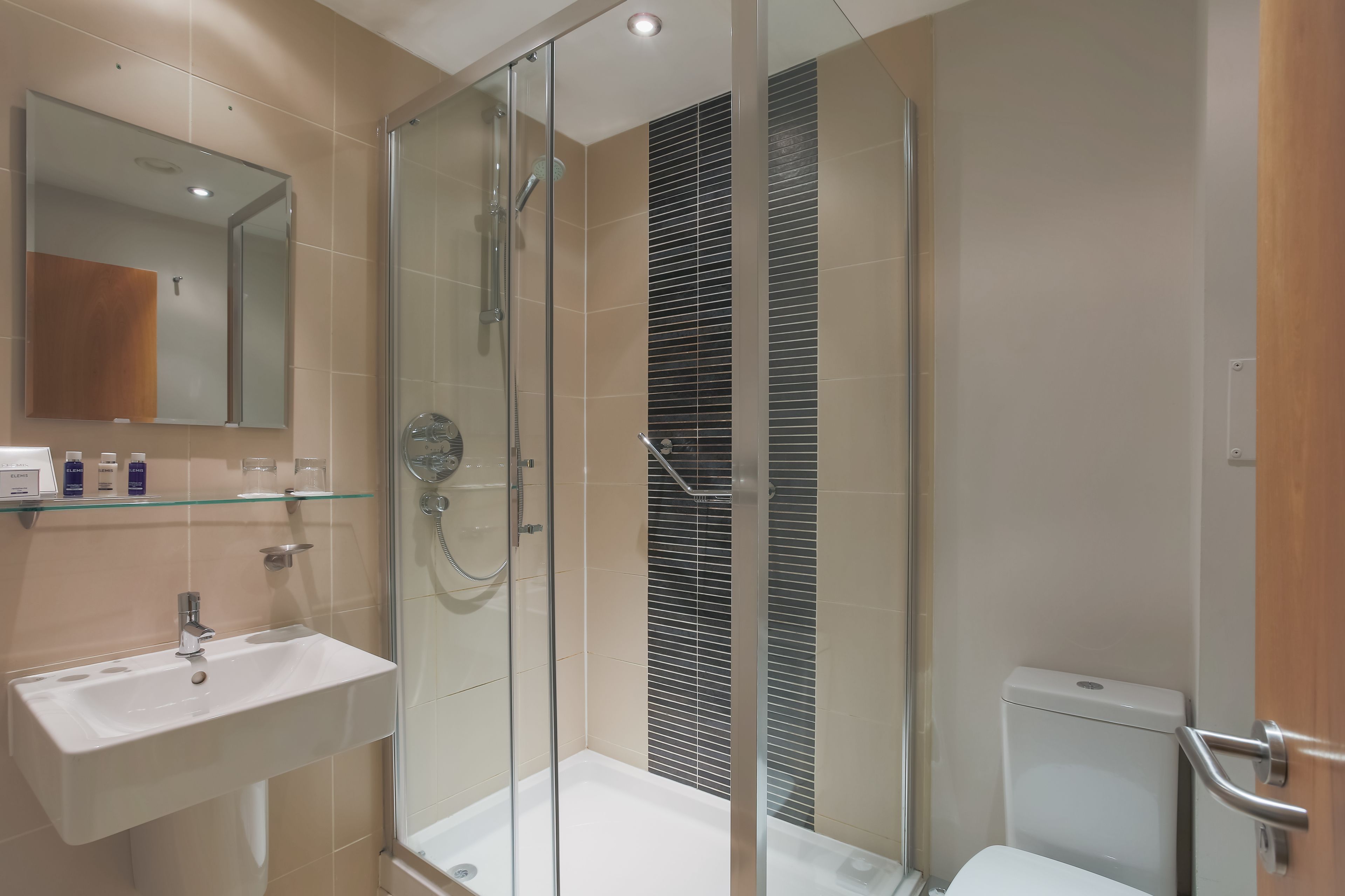 A modern bathroom with a glass-enclosed shower, a white sink, and a toilet.