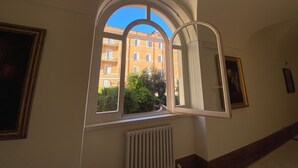 Una habitación con un amplio ventanal de arco que da a un edificio y follaje.
