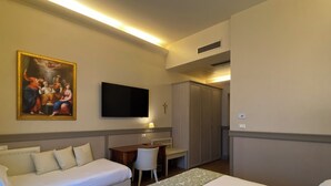 Habitación de hotel con dos camas, un escritorio, una silla, un televisor y un cuadro en la pared.