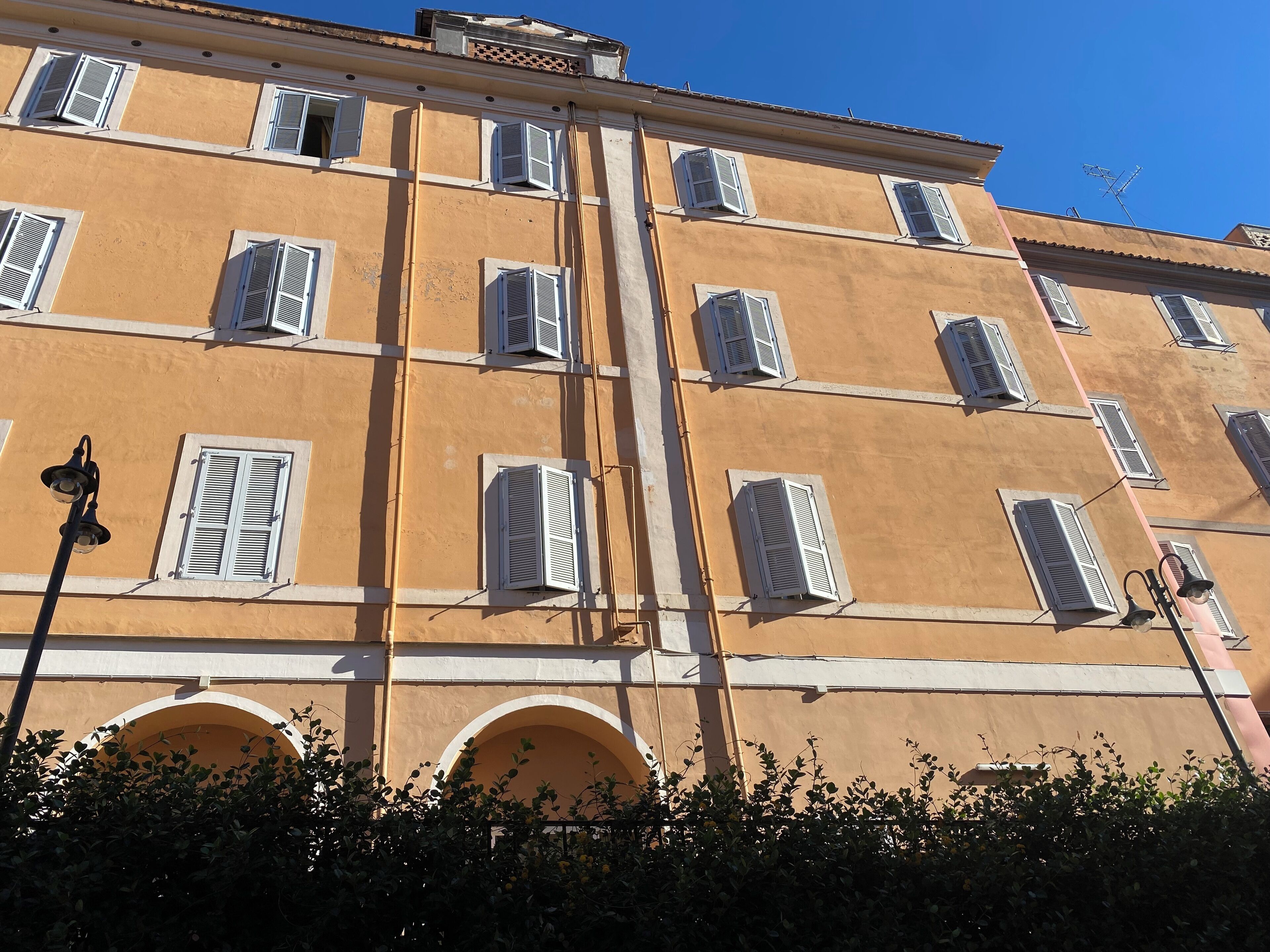 Ein mehrstöckiges Gebäude mit Rundbogenfenstern und weißen Fensterläden.