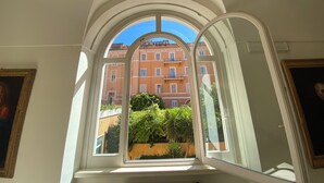 Una habitación con un amplio ventanal arqueado que da a un edificio con balcones y vegetación.