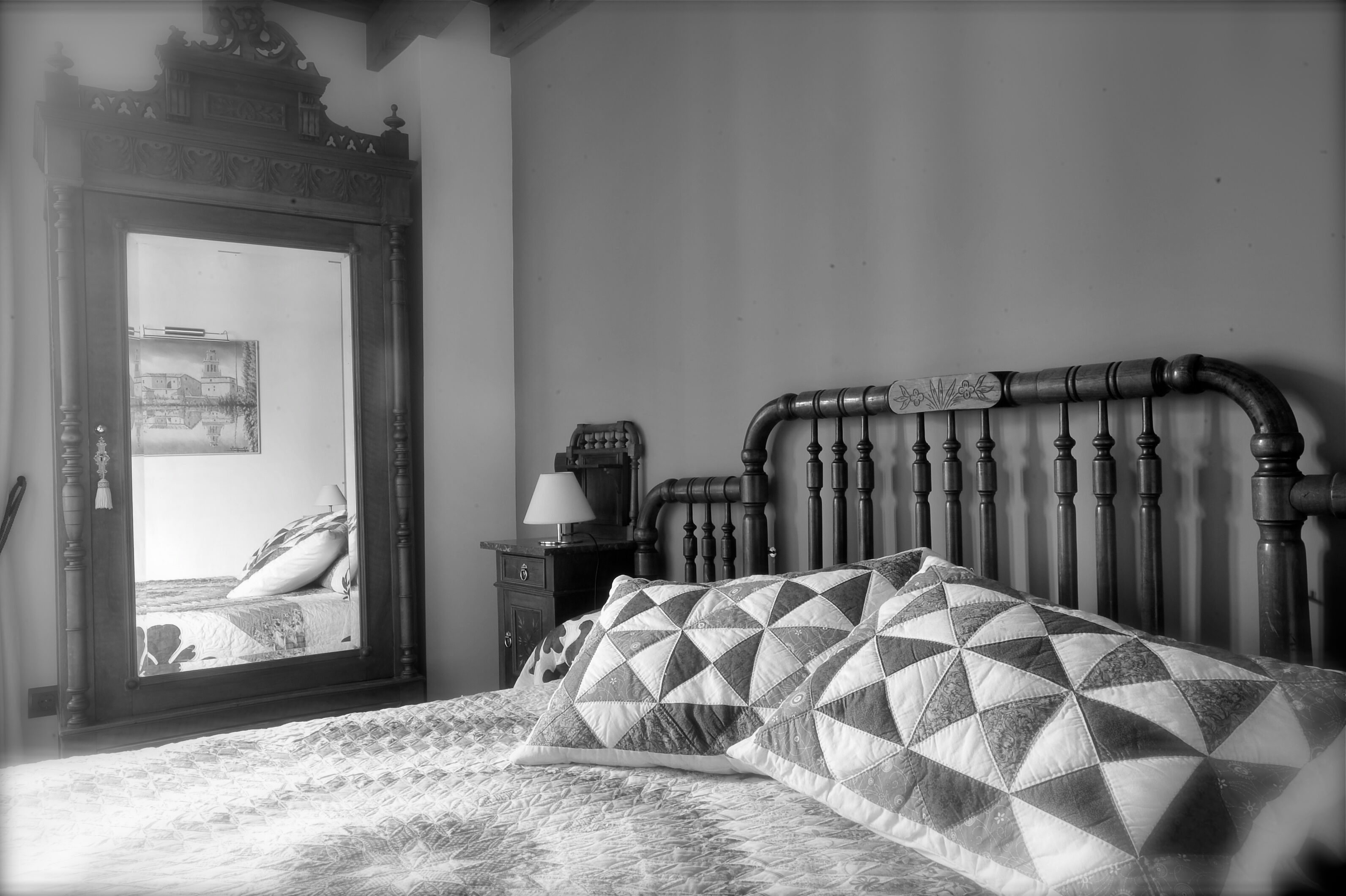 Un dormitorio con una cama, un espejo y una mesita de noche.