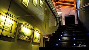 Una escalera con escalones de madera y luces azules que conduce a una habitación con cuadros en las paredes.