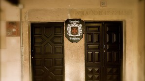 Fachada de edificio con dos puertas negras simétricas, un letrero con escudo y el número '20' sobre las puertas.